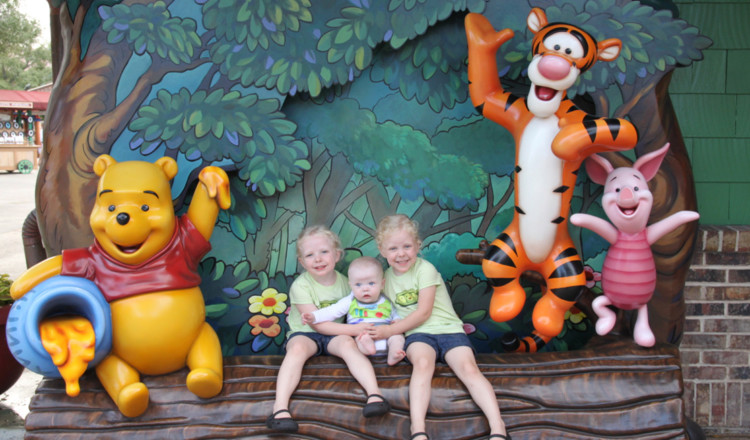 three kids pose with winnie the pooh, tigger, and piglet in a photo spot outside of the Walt Disney World parks