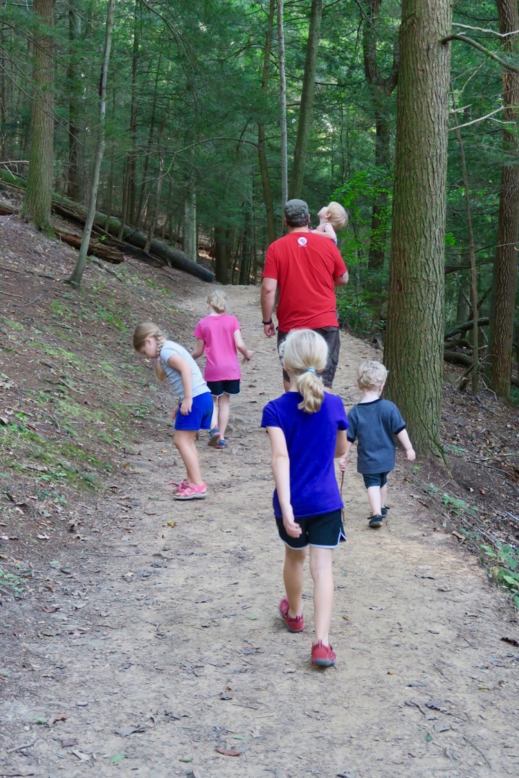 a group of kids hikes behind a man on a trail in Hocking Hills, near Logan, Ohio.