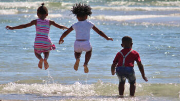 Siblings jumping into the ocean is part of the joy of traveling with your family, even when traveling while Black.